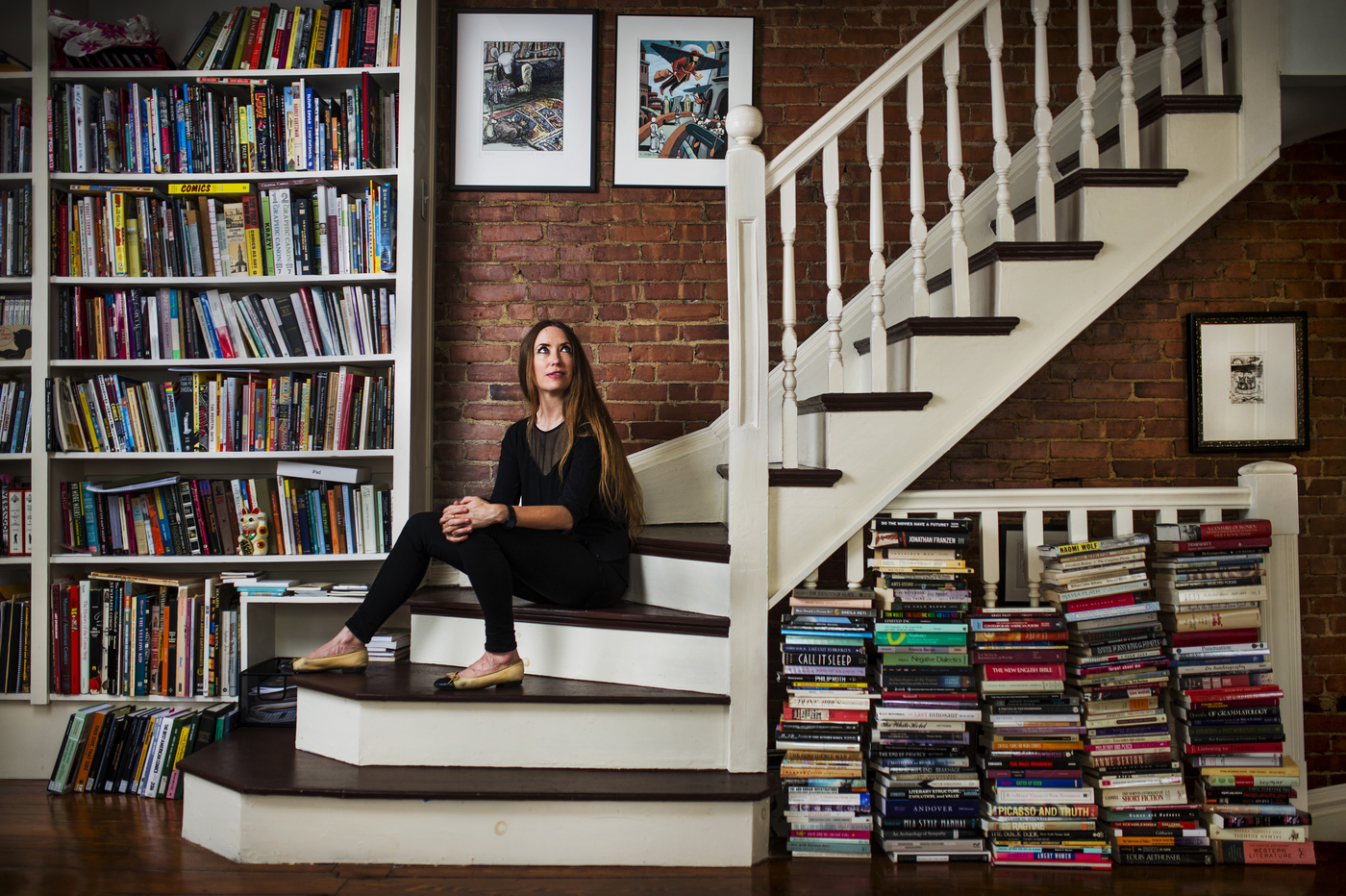 Woman sitting on staircase surrounded by books