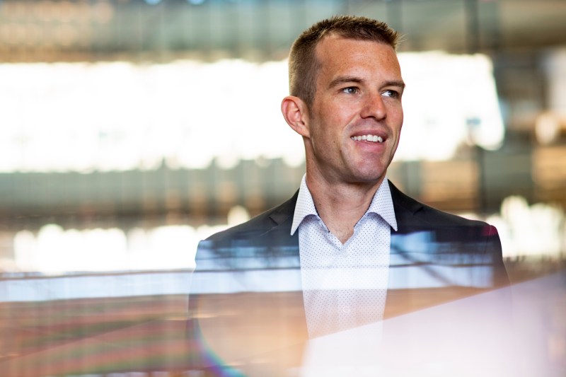 John Lowrey, assistant professor of supply chain management, smiles while looking off to the side, wearing a blue blazer.