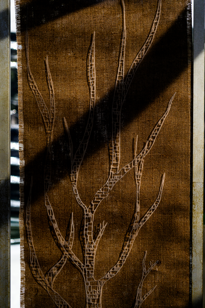 A panel with an etched tree illustration over a fabric background