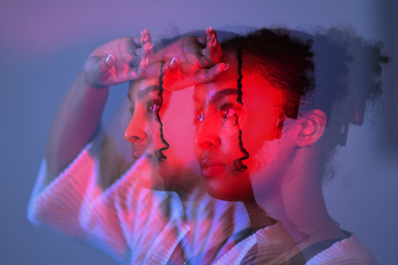 A woman lit up with pink and her hand on her forehead