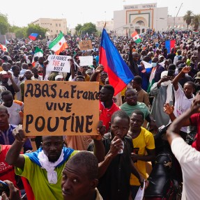 A crowd participates in a large march on a sunny day.