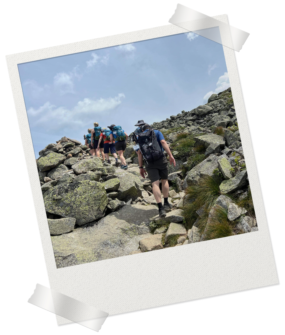 Decorative Polaroid frame containing image of hikers walking over rocky terrain in the sunlight.