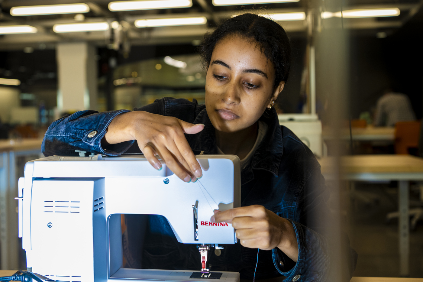 Student threading a sewing machine in the Makerspace at EXP.
