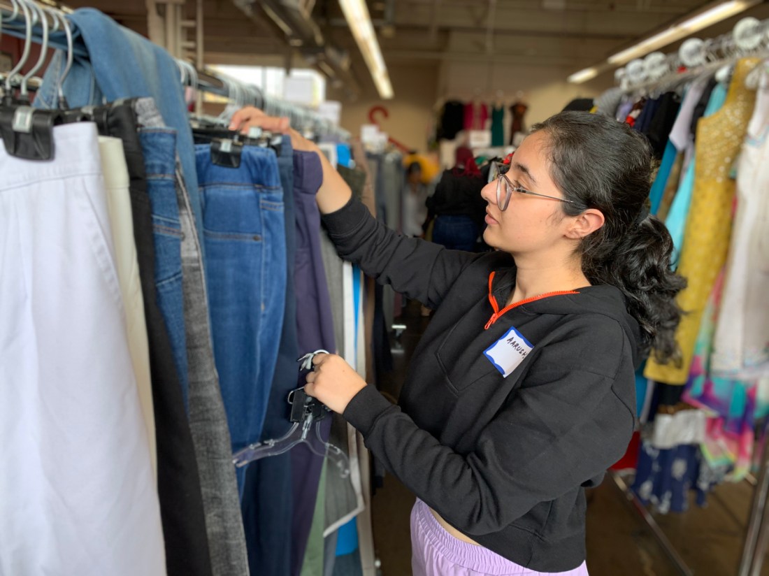 Student sorting through racks of clothing.