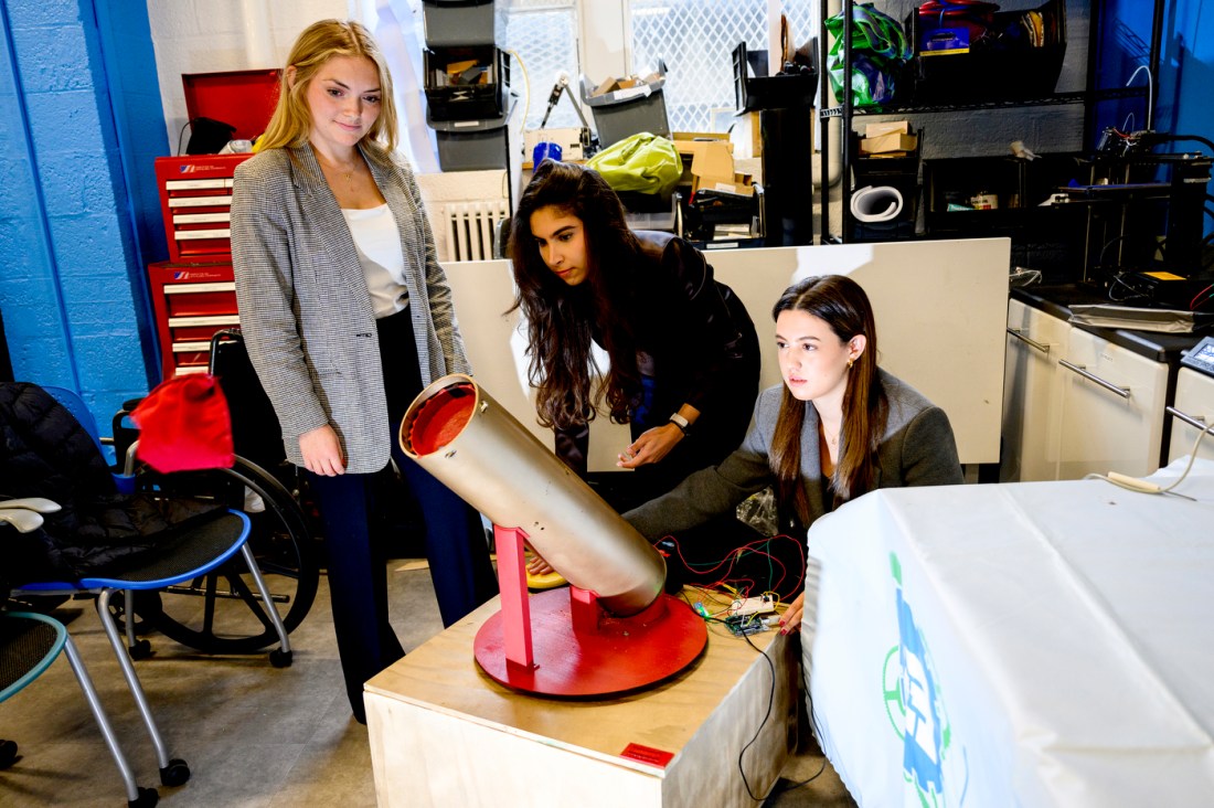 Students working on an engineering project that involves a long cylindrical tube.