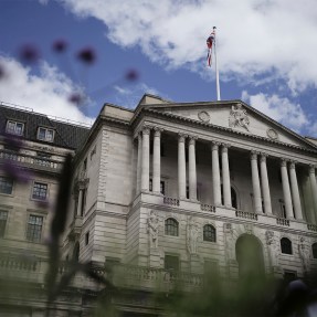 A large bank in London viewed outside on a slightly cloudy, blue sky day.