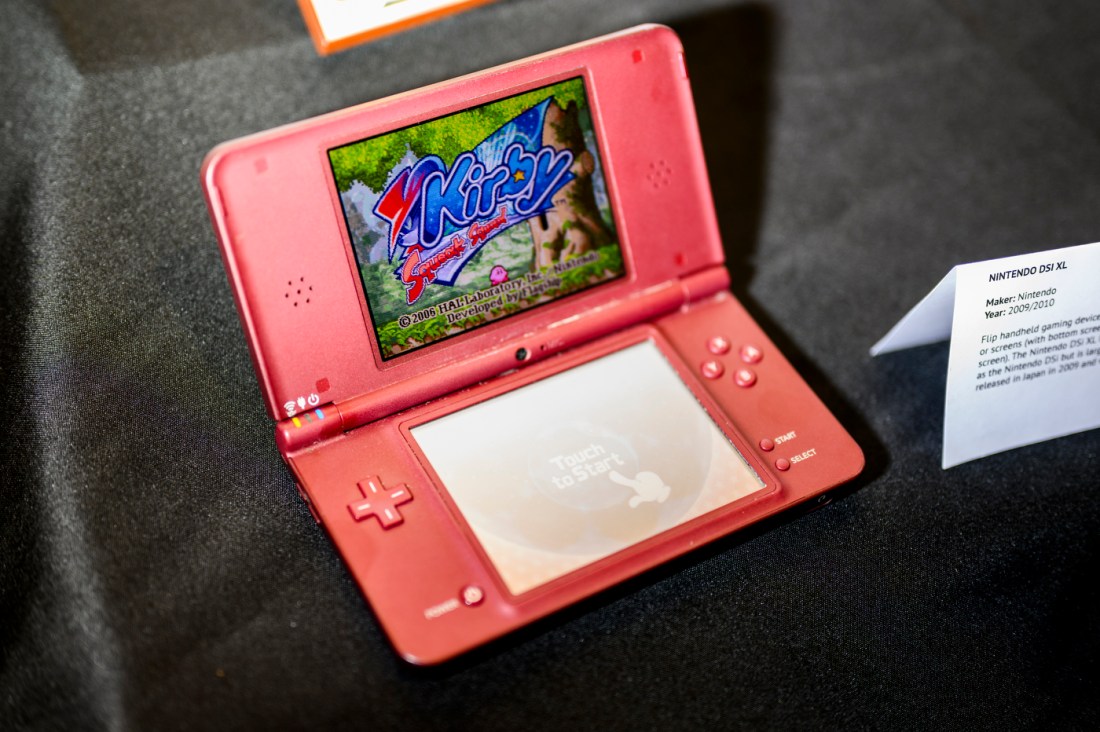 A coral colored Nintendo DS open to a Kirby game. 