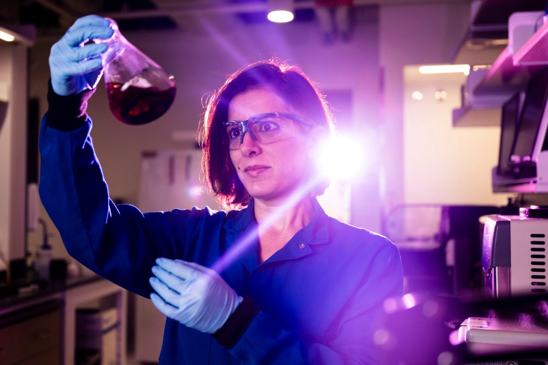 Leila Deravi holding a beaker full of a purple looking substance. 