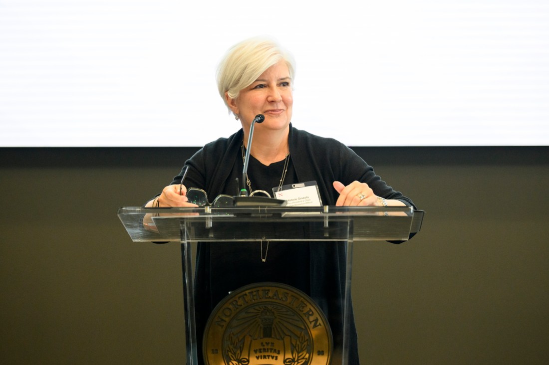 A member of the Northeastern community standing at a podium speaking into a microphone at the service recognition reception.