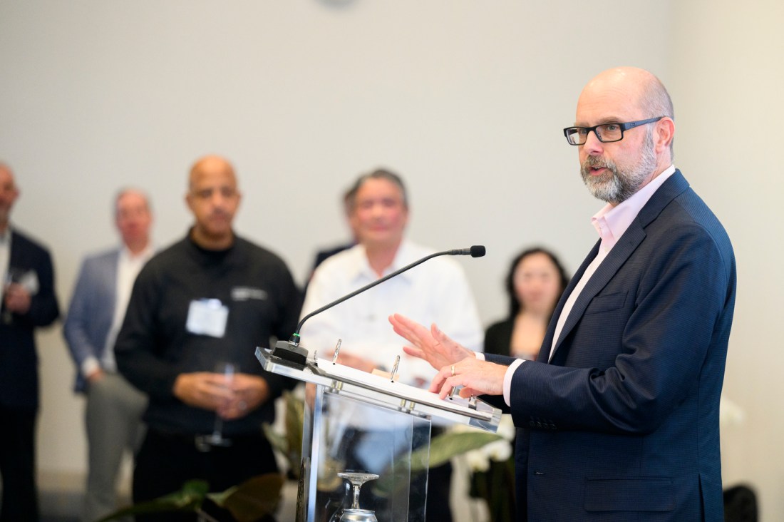A member of the Northeastern community standing at a podium speaking into a microphone. 