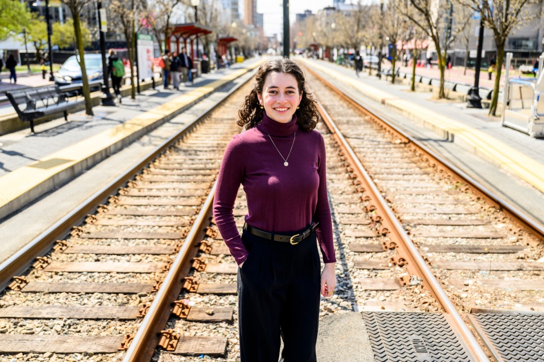 Portrait of Rachel Hocker standing in between the train tracks on the Boston campus. 