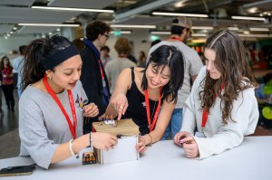 Three students working on an engineering project at a table.