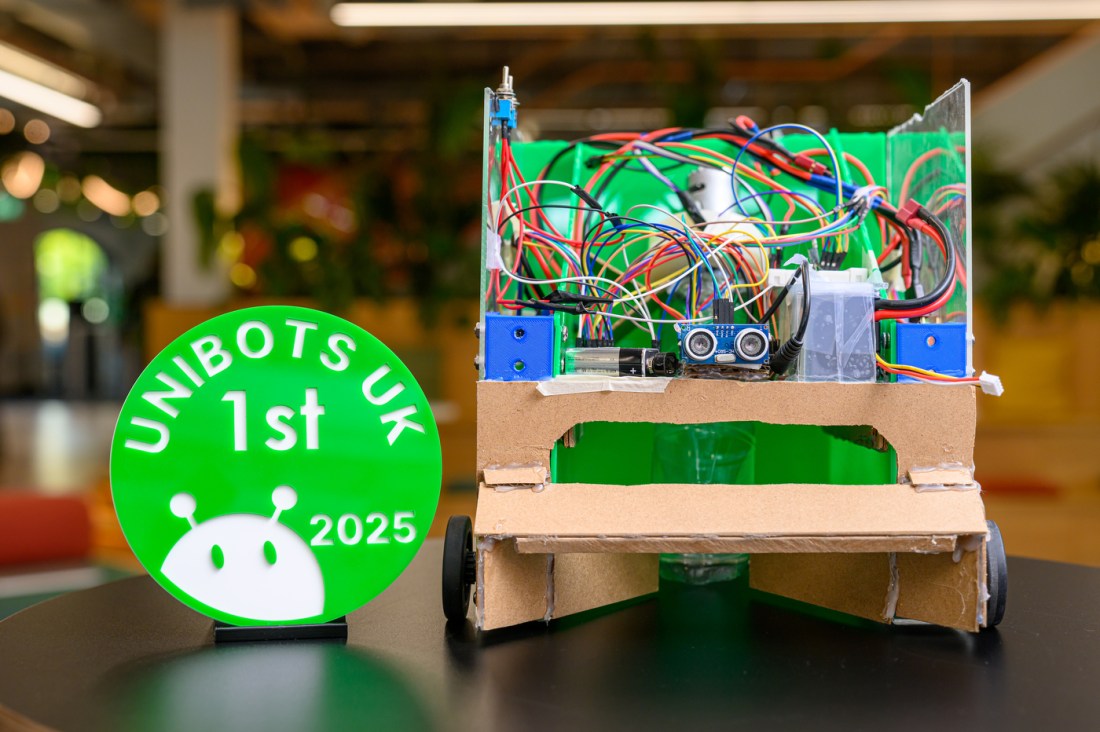The robot of the two Northeastern students that won first prize at the Unibots competition next to a green medal saying 'Unibots UK 1st'.