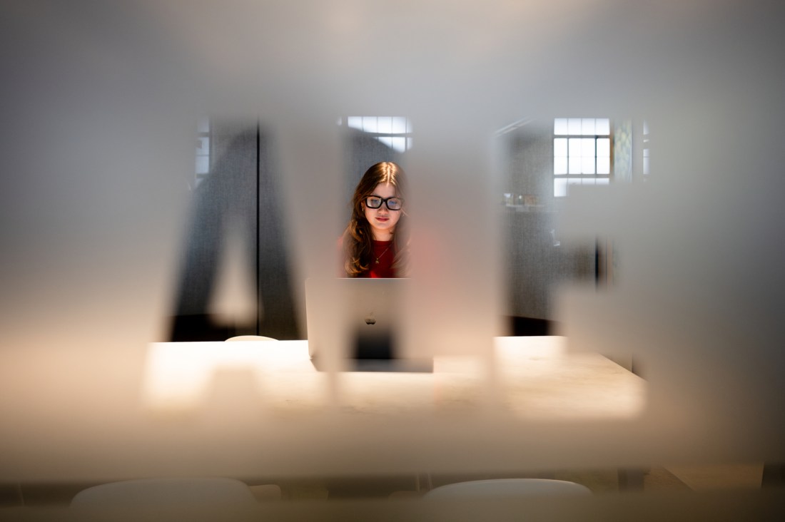 Student works on a laptop during a design co-op project in an office setting.