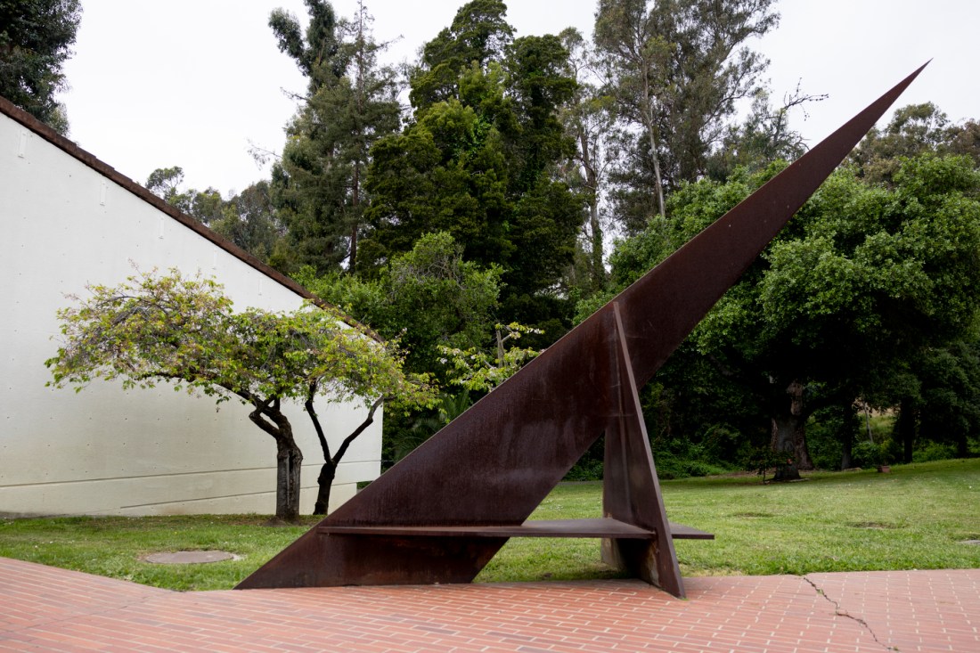 A large sundial outside on a green lawn next to a pathway.