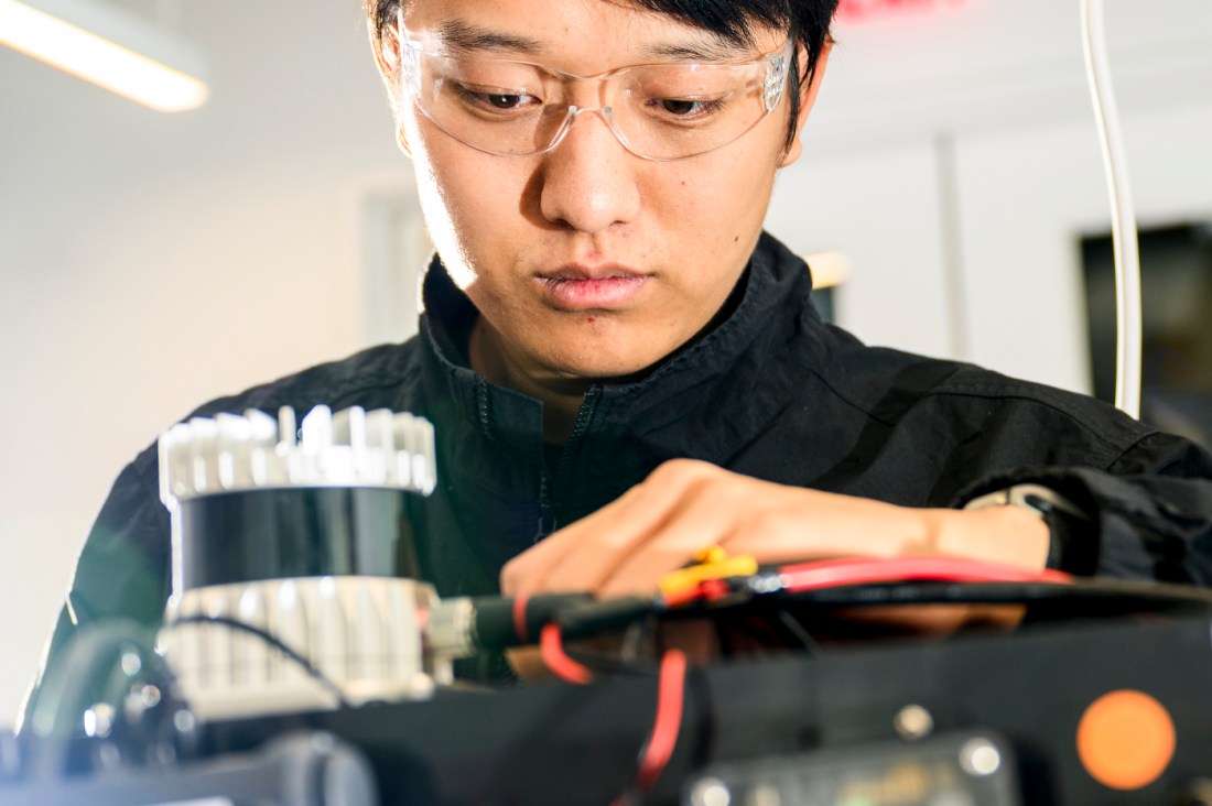 Zihao Dong wearing clear safety glasses installing an autonomy kit on a robot.