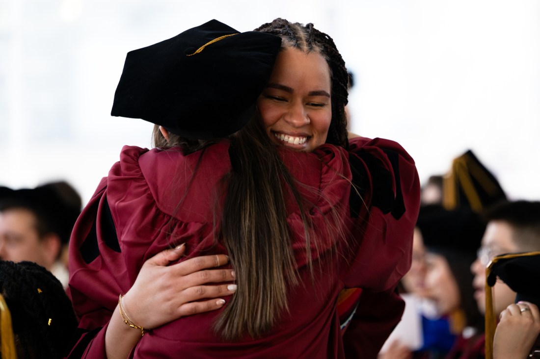Two PhD grads hugging each other.