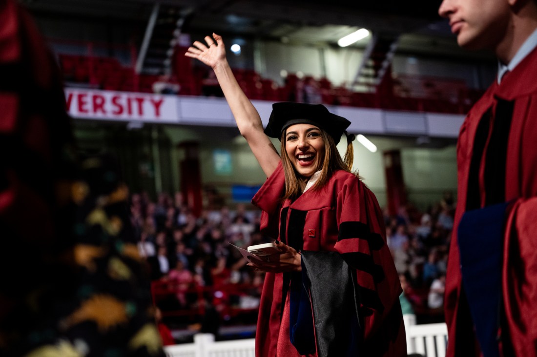 A PhD student waving their hand in the air at the hooding and commencement ceremony.