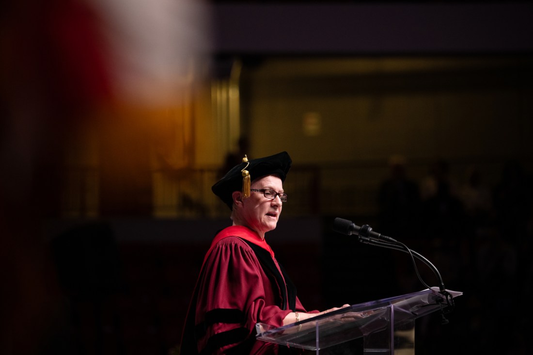 Margaret Faul speaking on stage at the PhD hooding and graduation ceremony.