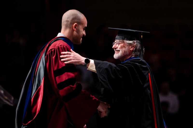 Two people greeting each other on stage at the PhD graduation and commencement.