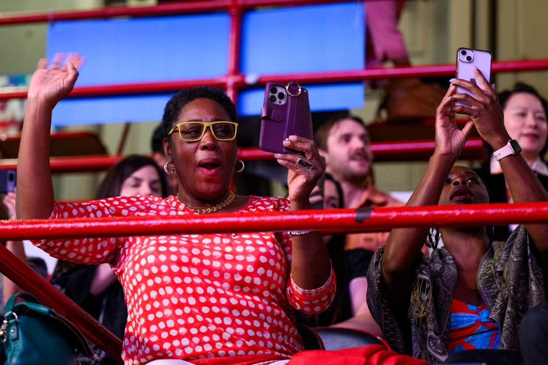 Audience members cheering while filming on their phones at the PhD ceremony.