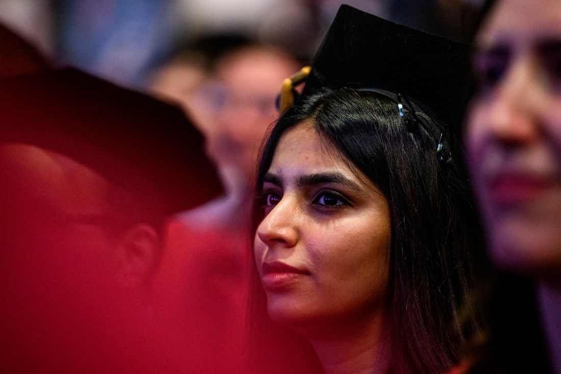 A PhD grad listening intently at their Hooding and Commencement ceremony.
