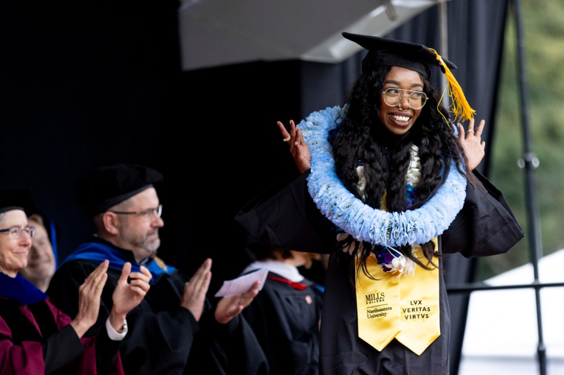 A graduate waving on stage at the Oakland commencement ceremony.