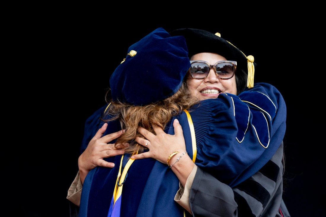 Two people hugging on stage at the Oakland commencement ceremony.