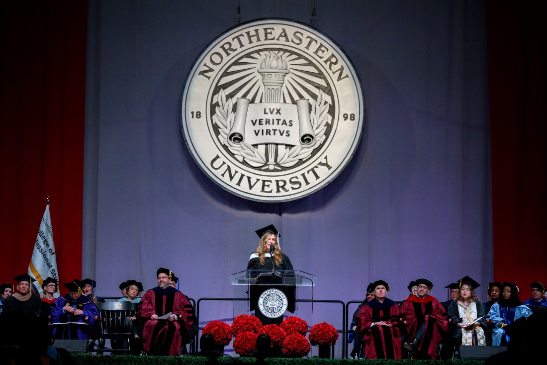 Alexandra Drane standing on stage at a podium wearing a cap and gown.