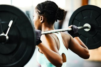 A person squatting with a barbell with two plates on either side at the gym.