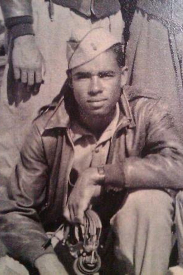 A close up of the previous photo of the airmen, showing Keel in uniform, kneeling in front of a plane.