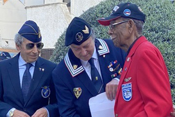Daniel Keel with his Tuskegee hat and in a decorated red jacket stands with others in ceremonial dress.