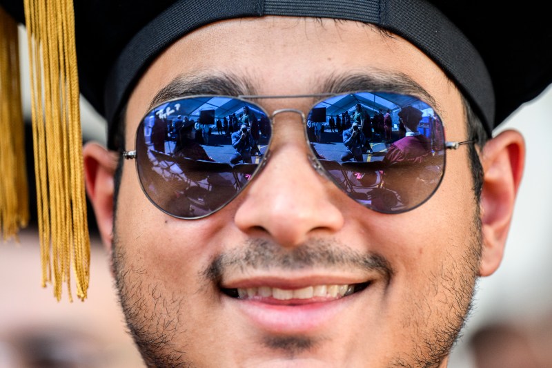 A closeup of a smiling grad wearing sunglasses
