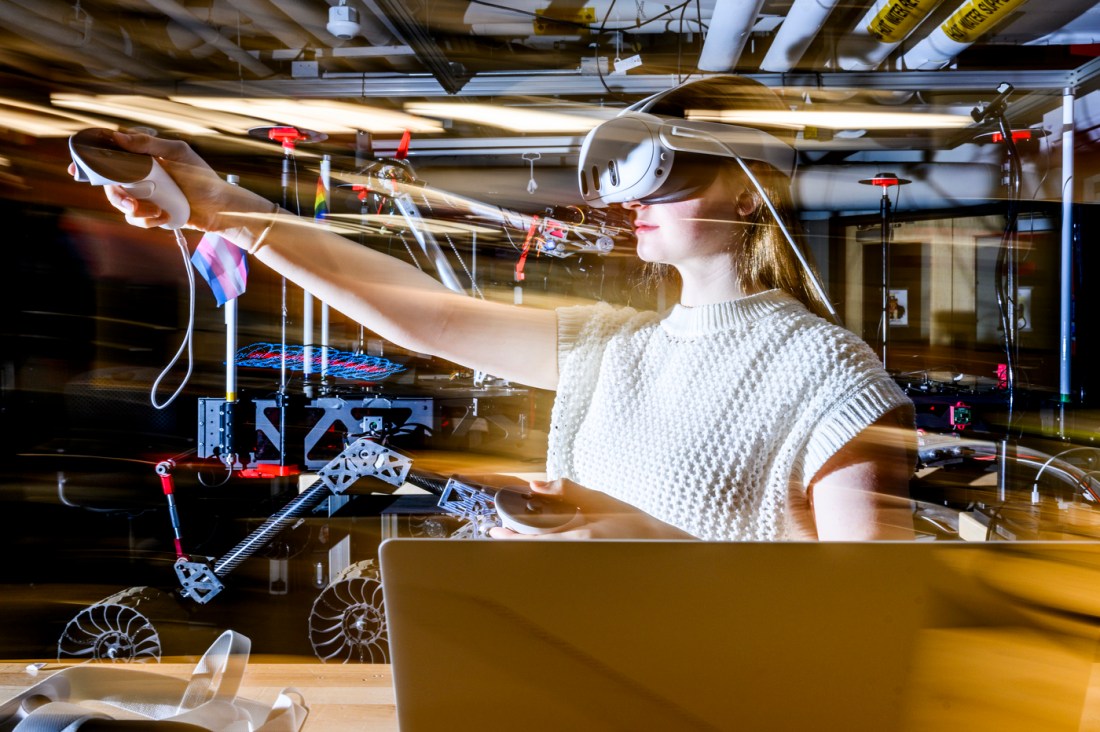 A person uses a virtual reality headset to work on a project in a lab setting.