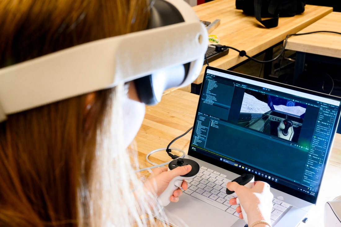 Person wearing a virtual reality headset works on a computer project in a lab setting for a NASA competition.