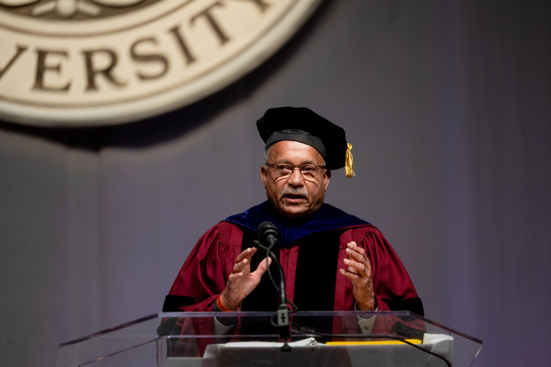 Ralph Martin wearing a cap and gown on stage at Matthews Arena.
