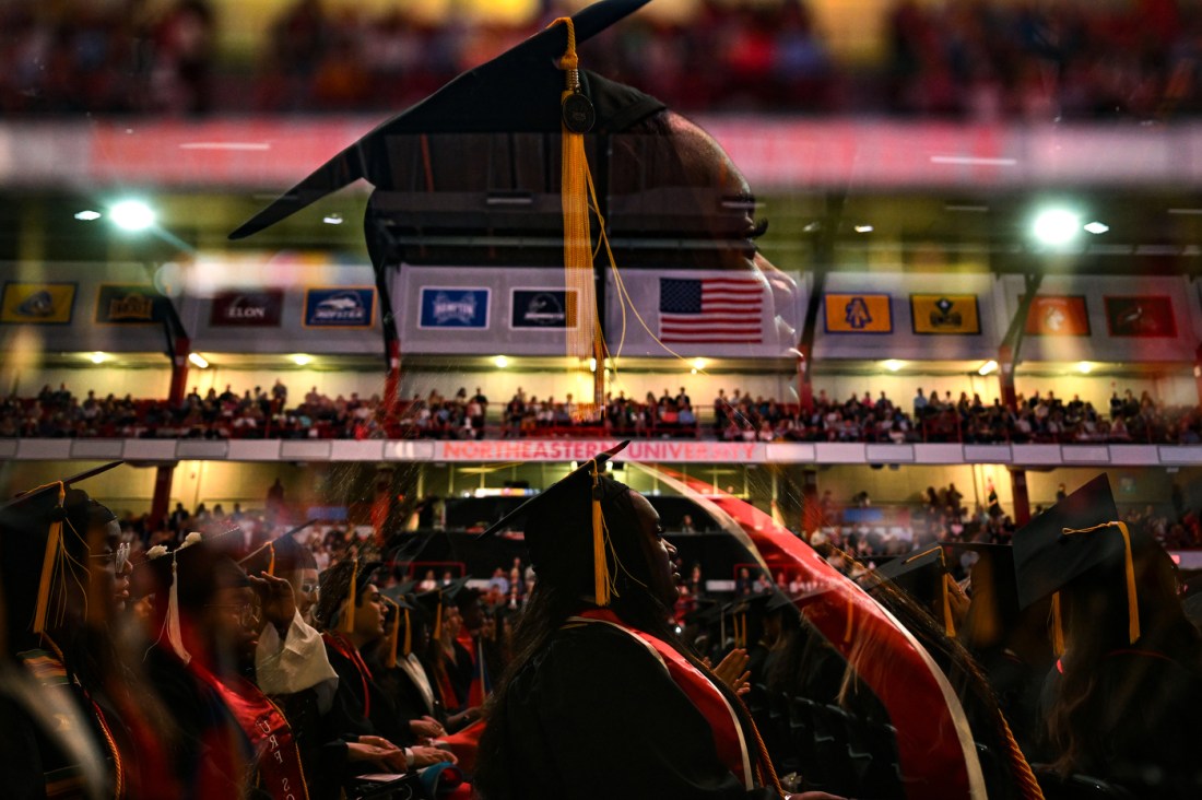 A Northeastern graduate sits during a ceremony at Matthews Arena.