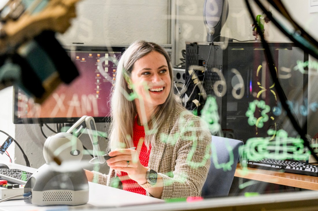 Julia Manczurowsky smiles while seated in a biomechanics lab surrounded by motion capture equipment and monitors.