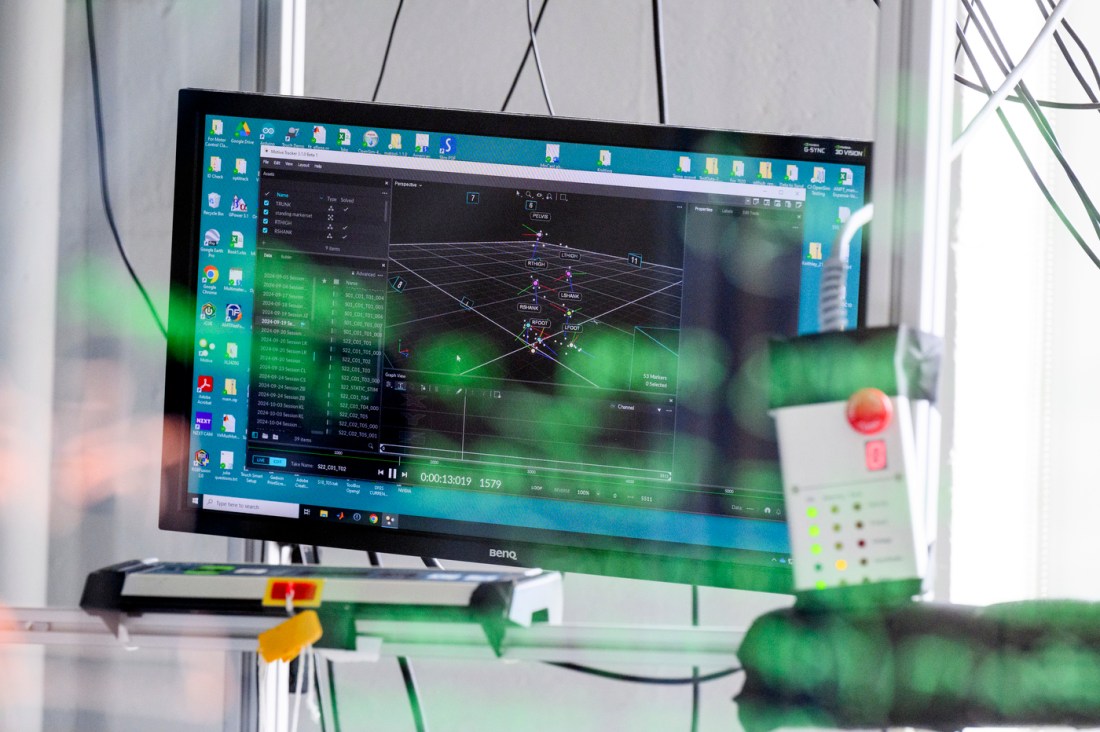 A computer screen displays data and motion analysis software with green reflections overlaying the monitor.