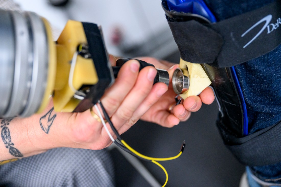 Close-up of a research participant's leg wrapped in motion sensors as a hand secures the equipment.