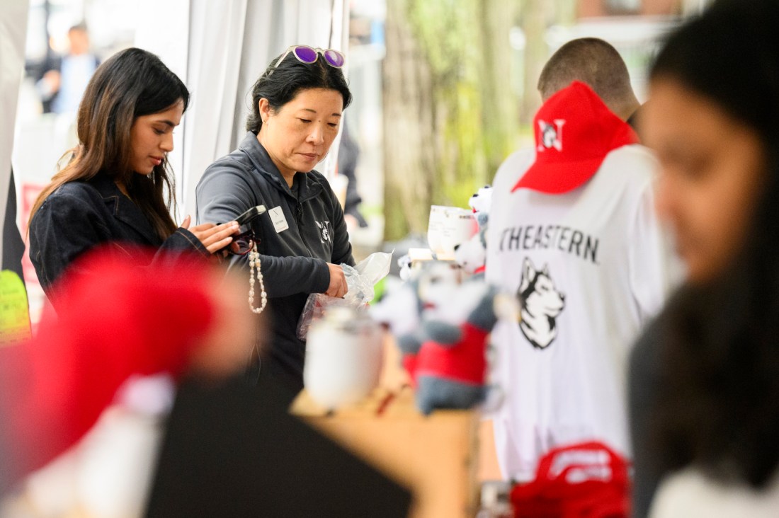 Two people purchasing products from the Hursky merch tent.