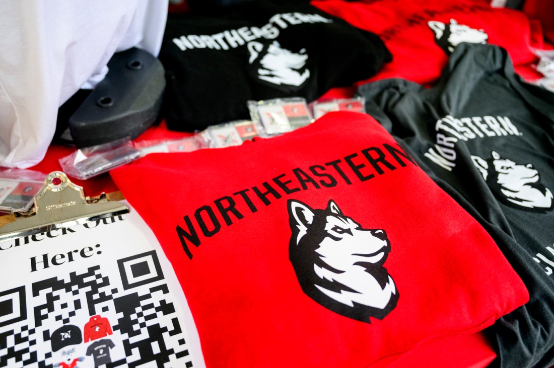 Stacks of Northeastern branded shirts laid out on a table.