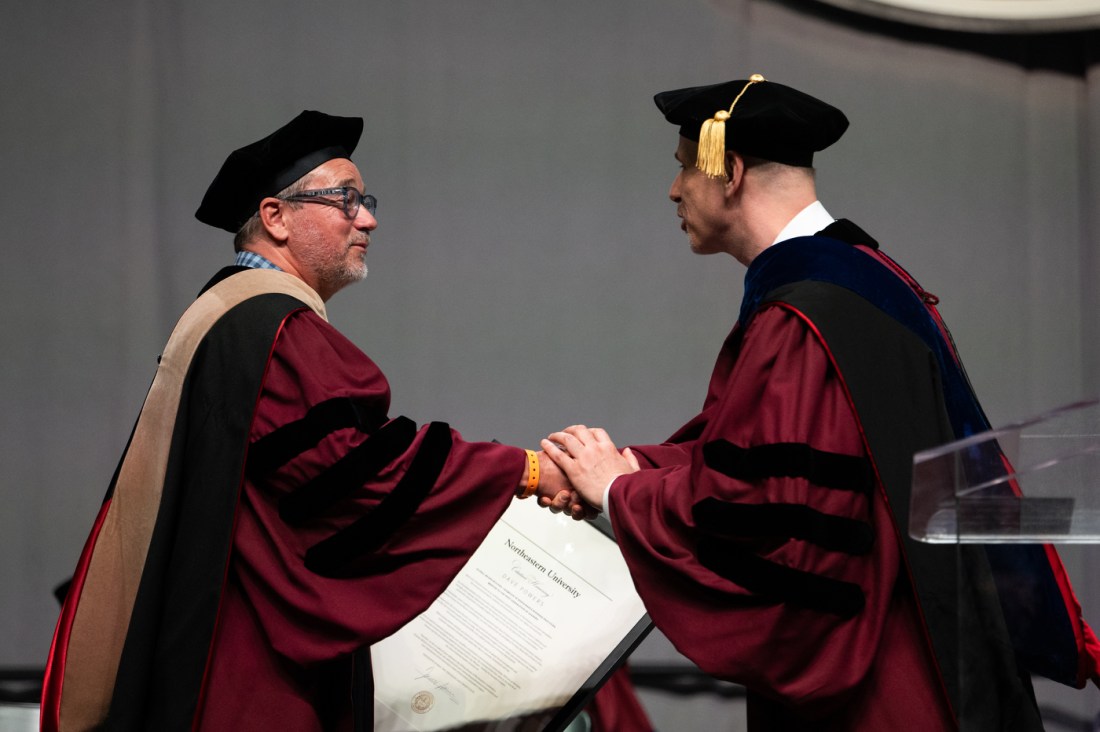 Former Deckers CEO interacts with university leadership during a commencement ceremony.