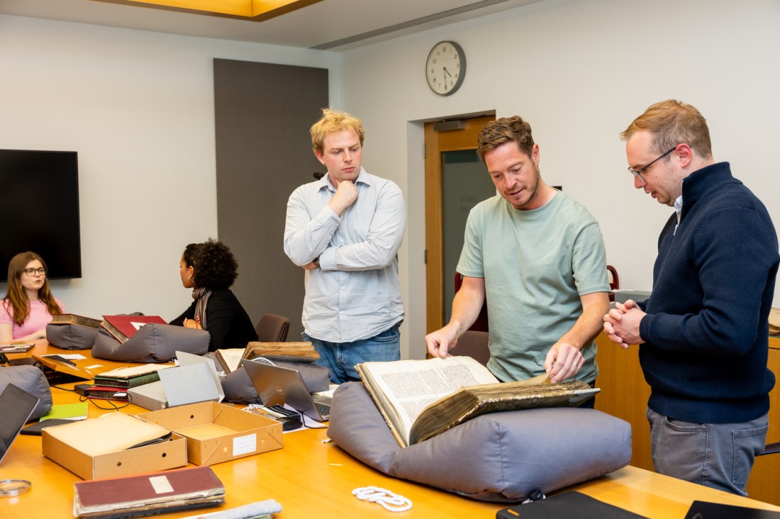 Researchers and students gather around rare books during a group archival session at Lambeth Palace Library.
