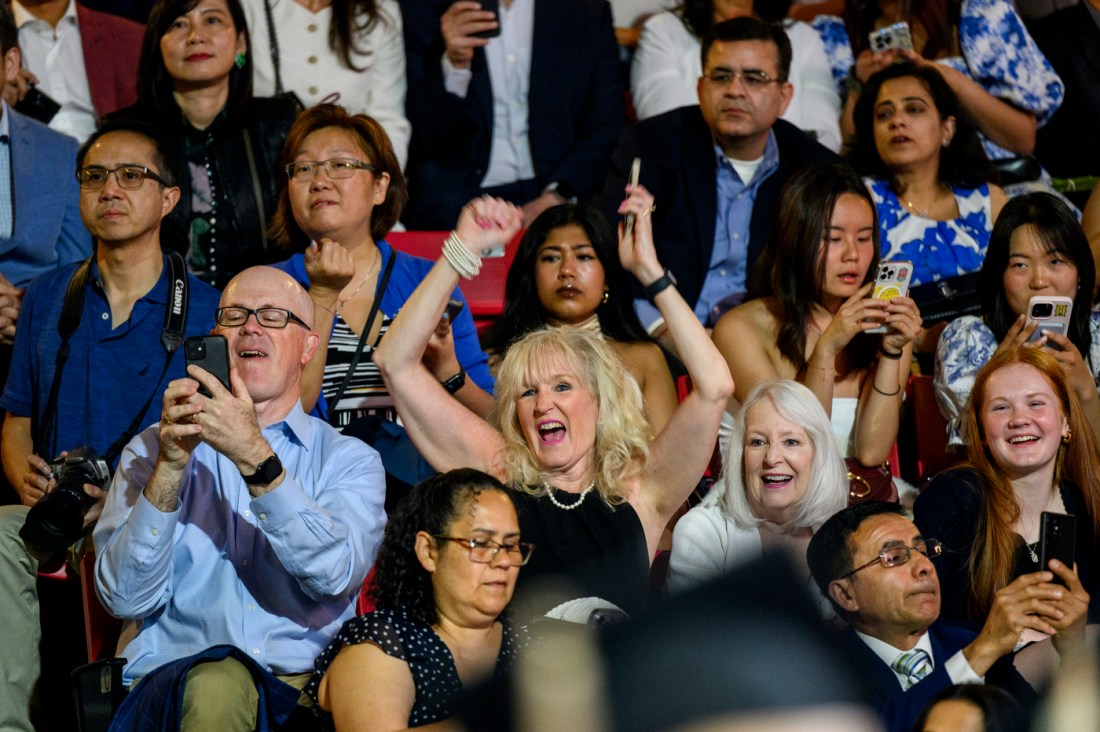 Audience members watch and take photos during a graduation ceremony.