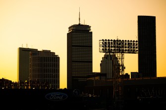 Silhouetted city skyline at sunset with a warm yellow sky in the background.