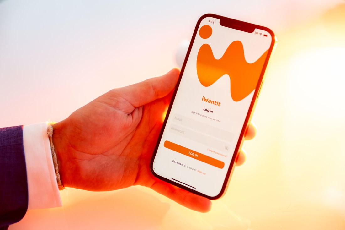 Alejandro Diez' hand holding up a phone open to his marketplace app, iWantIt.