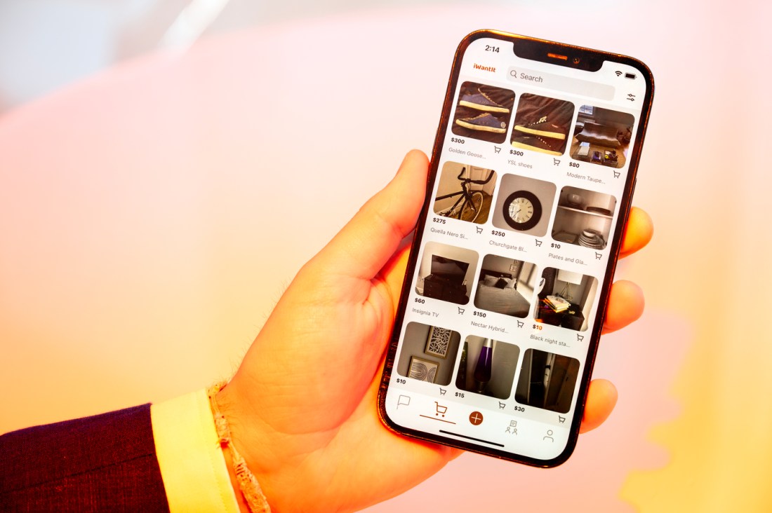 Alejandro Diez' hand holding a phone open to his student-only marketplace app, iWantIt.