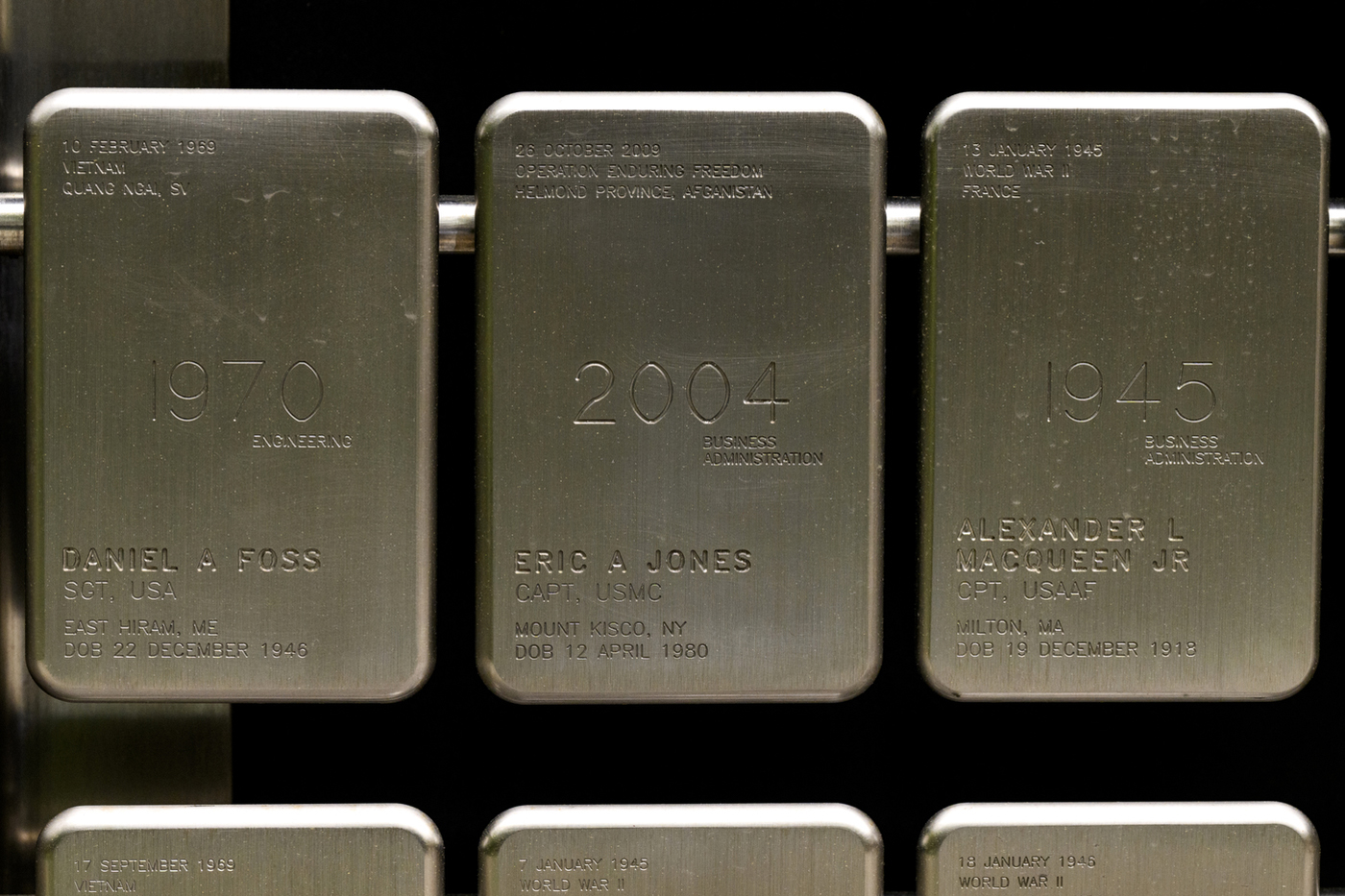 Three dog tags, engraved with the personal information of the veterans they represent, hang from a wall as part of the Veterans Memorial on Northeastern's Boston campus.