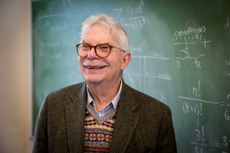 Portrait of Richard Porter in front of a chalkboard with math equations written on it.